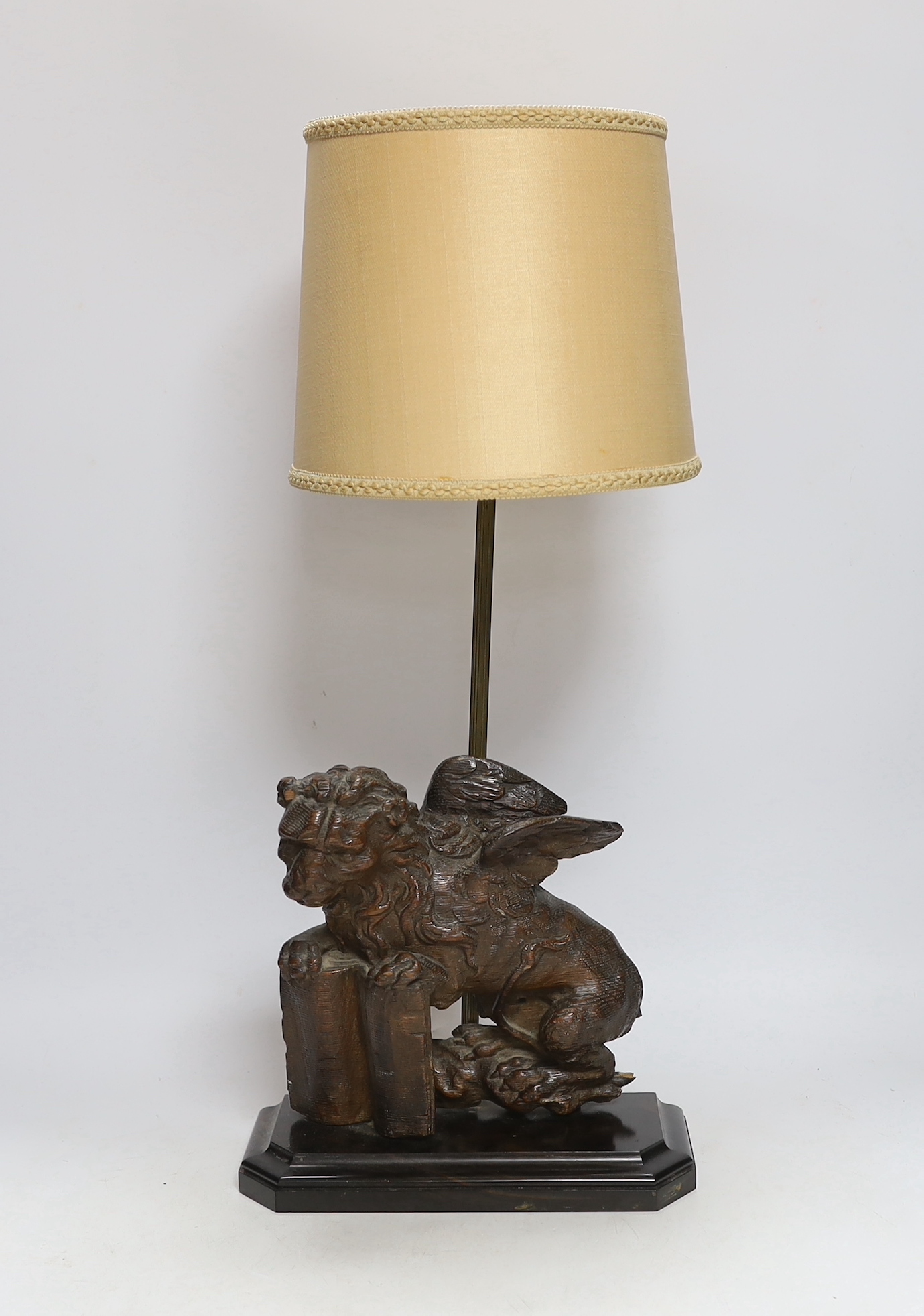 An 18th century oak carving of a Heraldic lion, now as a lamp, 55cm high including shade